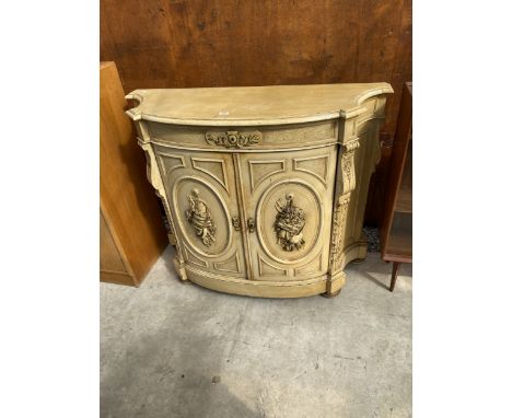 A VICTORIAN STYLE CREAM PAINTED BOW FRONTED TWO DOOR SIDE CABINET WITH FRIEZE DRAWER AND CARVED APPLIED DECORATION TO DOORS, 