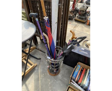 A METAL STICK STAND WITH AN ASSORTMENT OF STICKS AND UMBRELLAS ETC