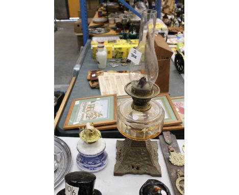 A LARGE VINTAGE OIL LAMP WITH A CAST BASE, AMBER RESEVOIR AND CHIMNEY, PLUS A GERMAN CERAMIC BLUE AND WHITE OIL LAMP BASE