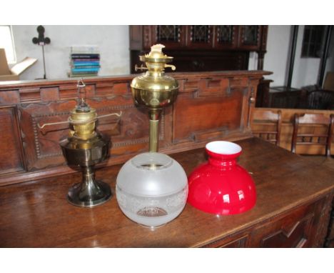 A brass fluted column oil lamp with frosted shade and a brass 'Aladdin' oil lamp with red glass shade, 44cm & 33cm