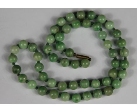 A jade bead necklace, the fifty four beads (each of approx 8mm diameter) all knotted on green cotton and with an attached bar