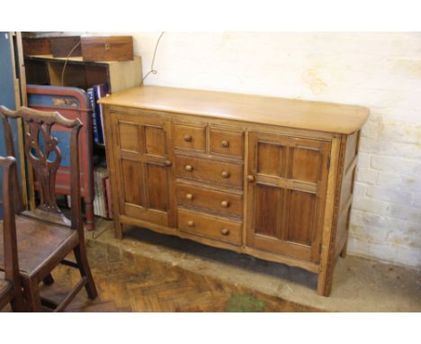 A light oak cabinet with drawers flanked by two cupboards, 90cm x 139cm x 50cm