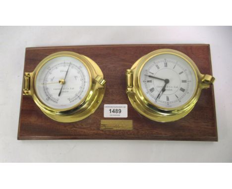 Garrard & Co., small circular brass cased ship's barometer and clock, mounted to a rectangular mahogany backBattery operated 