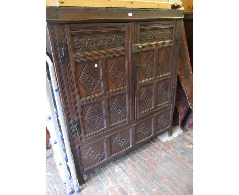 Oak two door cupboard, constructed from 17th Century panelling, with carved decoration, stile end supports, and later brass l