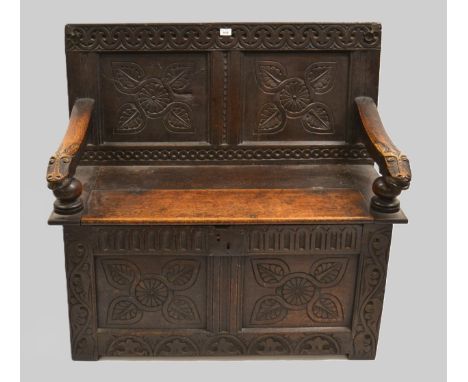17th Century and later oak hall bench, the panelled back with carved arm rests and hinged seat, on stile end supports, 108cm 