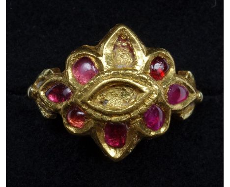 A YELLOW METAL RING, SET WITH SEVEN FREE-FORM CABOCHON RUBIES (TWO STONES MISSING), IN A CLOSED BACK SETTING, FINGER SIZE K 1