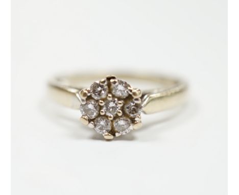 A 750 white metal and seven stone diamond set circular cluster ring, size M, gross weight 3.2 grams.