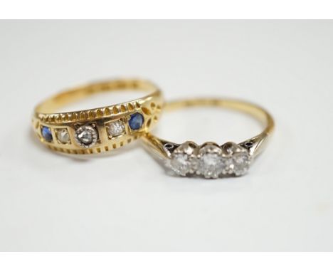 An 18ct, plat and three stone diamond set ring, size K and a late Victorian 18ct gold three stone diamond and two stone sapph