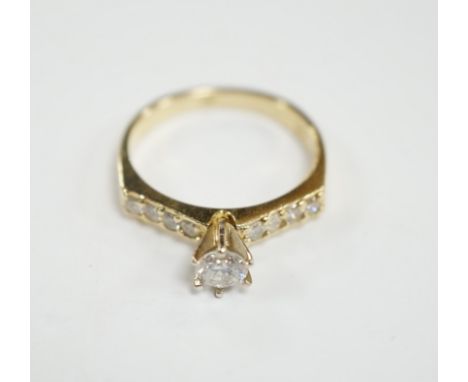 A modern 14k and single stone diamond set ring, with diamond chip set shoulders, size M, gross weight 2.7 grams.