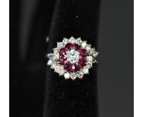 A white gold or platinum diamond and ruby cluster ring in flower type setting, the centre brilliant cut diamond surrounded by