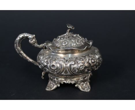 A William IV silver mustard pot of bulbous form with embossed decoration throughout on four feet with floral finial by John, 
