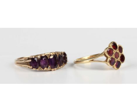 A 9ct gold and amethyst five stone ring, mounted with a row of graduated oval cut amethysts with pairs of diamond point at in