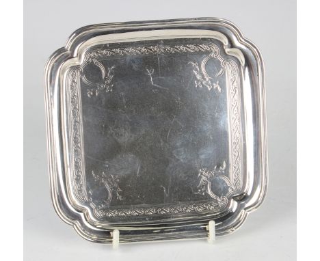 A George V silver card salver of square form with lobed corners, engraved with scrolls, raised on lobed feet, London 1910 by 