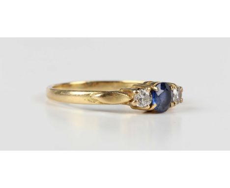 An 18ct gold, sapphire and diamond three stone ring, claw set with a circular cut sapphire between two circular cut diamonds,