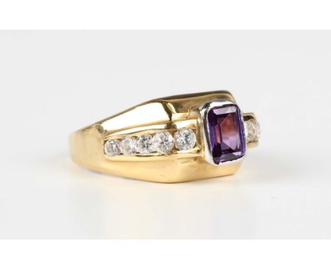 A gold ring, mounted with a rectangular cut synthetic mauve sapphire between colourless gem set tapered shoulders, detailed '