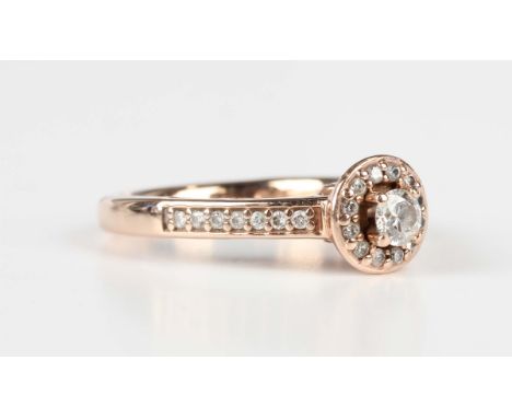 A rose gold and diamond ring, claw set with the principal circular cut diamond within a surround of smaller circular cut diam