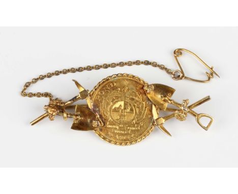 A South African 'gold prospector' brooch, the centre mounted with a half-pond 1896, the sides with nugget, pick and shovel mo