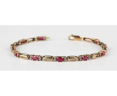 A 9ct gold, ruby and diamond bracelet, each link claw set with a central oval cut ruby between a pair of circular cut diamond