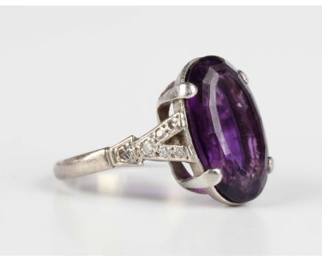 A white gold ring, claw set with an oval cut amethyst between diamond set 'V' shaped shoulders, detailed '18ct', weight 5.7g,