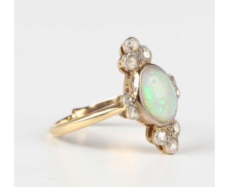 A gold, opal and diamond ring, collet set with the oval opal between two trefoil shaped motifs, mounted with rose cut diamond