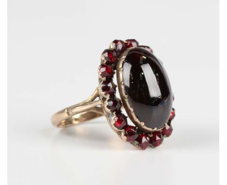 A gold and Bohemian garnet oval cluster ring, mounted with the principal carbuncle garnet within a surround of rose cut garne