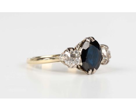 A gold, platinum, sapphire and diamond three stone ring, claw set with the oval cut sapphire between two cushion cut diamonds