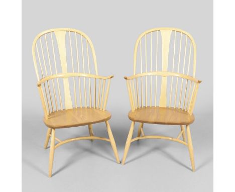 A pair of light elm and beech windsor chairs with turned spindle supports, supported with a curved cross stretcher. Both with