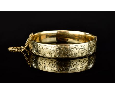 Edwardian Period 9ct Gold / Metal Core Hinged Bangle with Safety Chain. Chased Floral Decoration to Front, Marked 9ct Gold an