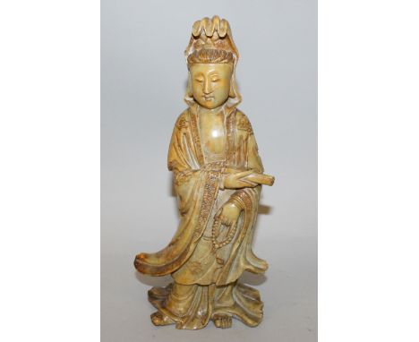 A 19TH CENTURY CHINESE CARVED SOAPSTONE FIGURE OF GUANYIN, her flowing robes engraved with cloud scrolls, the deity holding a