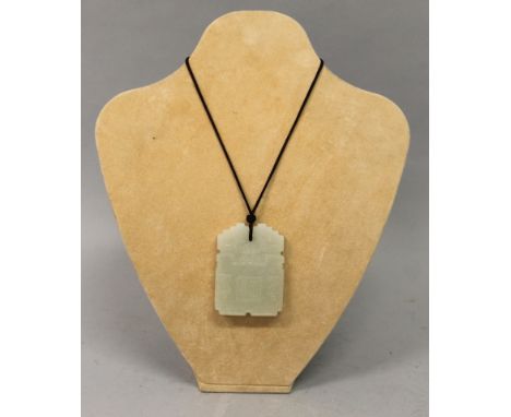 A CHINESE CELADON JADE-LIKE PENDANT, of archaic style with a shaped edge, one side with a seal mark, 2.6in high x 1.9in wide.