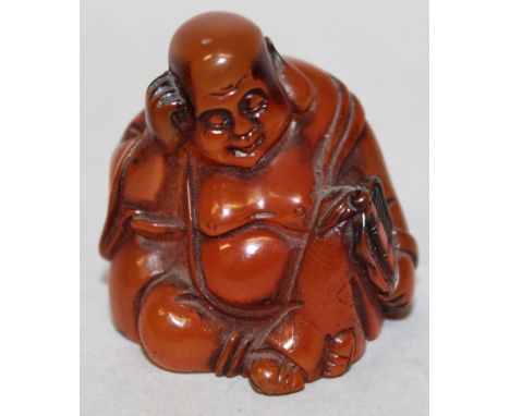 AN UNUSUAL SIGNED JAPANESE AMBER-LIKE NETSUKE OF HOTEI, seated with his head resting on one hand, 1.8in high.