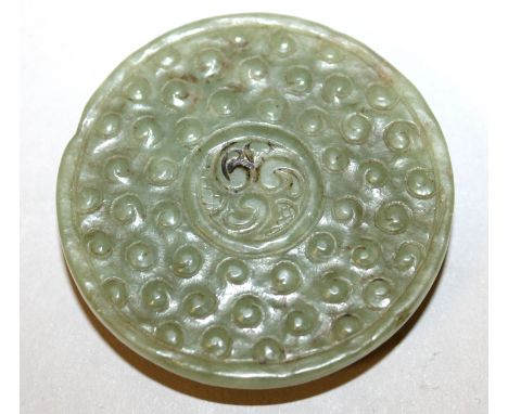 A CHINESE GREEN JADE BI DISC, of archaic design with studs enclosing a small circular panel, the sides chamfered, 2.1in diame