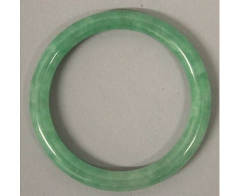 A CHINESE APPLE-GREEN JADE-LIKE BANGLE, 2.6in diameter, the inner rim 2in diameter. 
