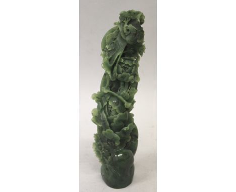 AN ELABORATE PIERCED CHINESE SPINACH GREEN JADE-LIKE MODEL OF EXTENDED FOLIAGE, sprouting from rockwork and surmounted by a p
