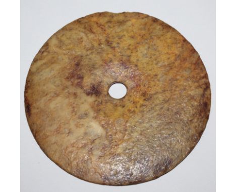 AN ARCHAIC STYLE JADE-LIKE BI DISC, of larger than average size, one surface carved in low relief with a small stylised motif