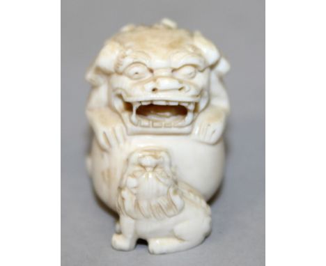 A 19TH/20TH CENTURY CARVED IVORY NETSUKE OF A KARASHISHI, leaning on a large ball and in the company of its pup, 1.5in long &