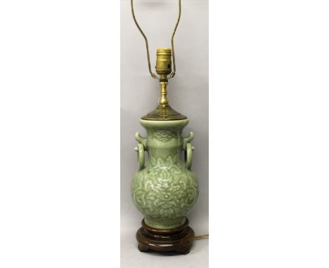 A CHINESE MOULDED CELADON PORCELAIN VASE, fitted for electricity, the sides of the vase decorated with scroll and leaf stemme