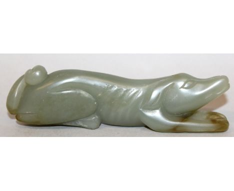A CHINESE GREEN JADE-LIKE MODEL OF A HOUND, lying stretched out with protruding ribs, 4.2in long. 