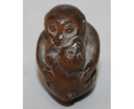 A 19TH CENTURY JAPANESE CARVED WOOD NETSUKE OF A MONKEY EMBRACING ITS YOUNG, 1.75in long & also 1.75in high.