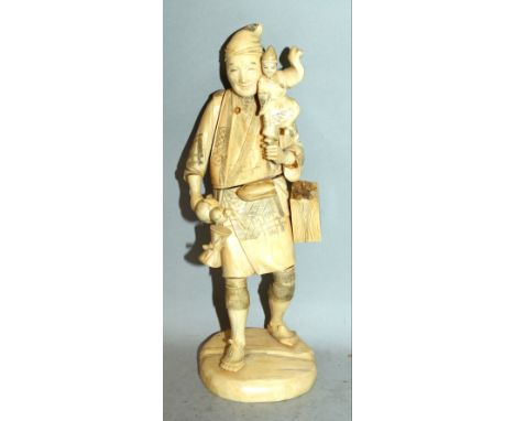 AN EARLY 20TH CENTURY JAPANESE SECTIONAL IVORY OKIMONO OF A STREET ENTERTAINER, holding a puppet and a gourd, a drum strapped