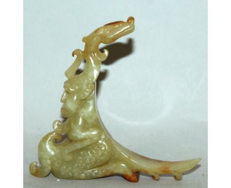 A CHINESE CELADON GREEN JADE-LIKE MYTHICAL FIGURE, of a dragon-headed creature with demonic humanoid features, the stone with