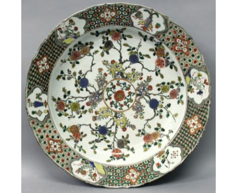 A CHINESE KANGXI PERIOD FAMILLE VERTE PORCELAIN CHARGER, circa 1700, painted to its centre with flowers and rockwork radiatin