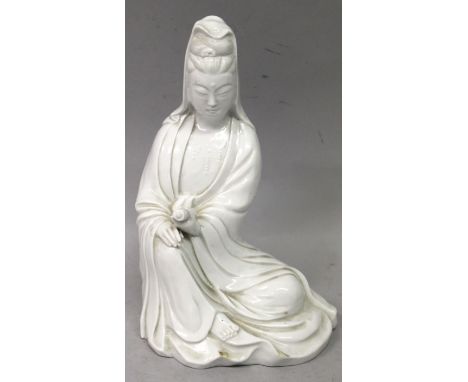 A 20TH CENTURY CHINESE BLANC-DE-CHINE PORCELAIN FIGURE OF GUANYIN, seated in flowing robes and bearing a scroll in one hand, 