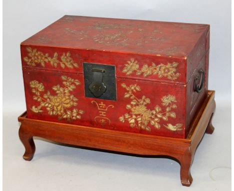 A 20TH CENTURY CHINESE GILT DECORATED RED GROUND LACQUERED WOOD RECTANGULAR CHEST, on a separate fitted hardwood stand, the h