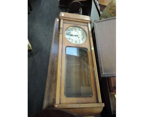 An early 20th century golden oak wall clock having circular silvered dial panel, pendulum and glass front  