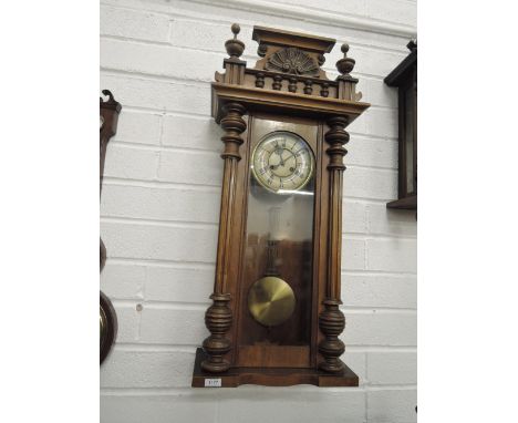 A late 19th century walnut cased Vienna wall clock having crest and spindle top over circular dial with Roman numerals and pe