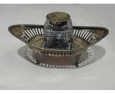 A Victorian silver ink stand of boat form having pierced gallery decoration and quadrafoil bracket feet with cut glass inkwel