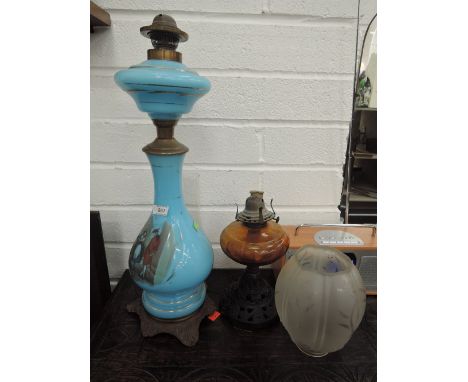 A Victorian blue glass oil lamp having transfer print and pictorial decoration and an Edwardian oil lamp having amber glass r