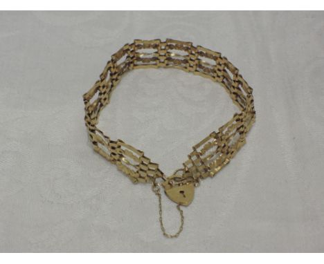 A yellow metal five bar gate bracelet stamped 375 having heart and scroll decoration and a padlock clasp weight 6.4g
