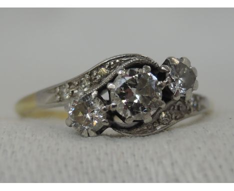 A lady's dress ring having a trilogy of diamonds, approx 0.5ct in claw setting to diamond set crossover shoulders on a yellow